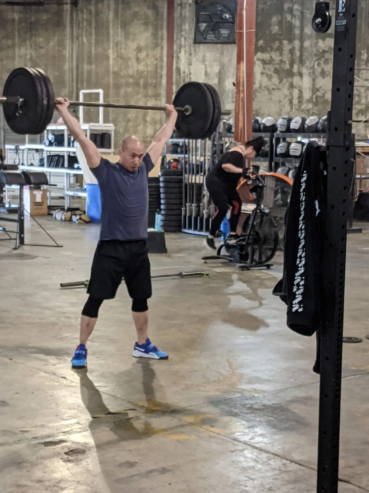 A Fit 901 member locking out a loaded barbell overhead in the warehouse gym.