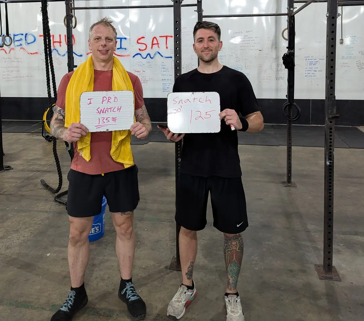 Matt and Josh at the rig holding their snatch PR boards: 135 lb and 125 lb.