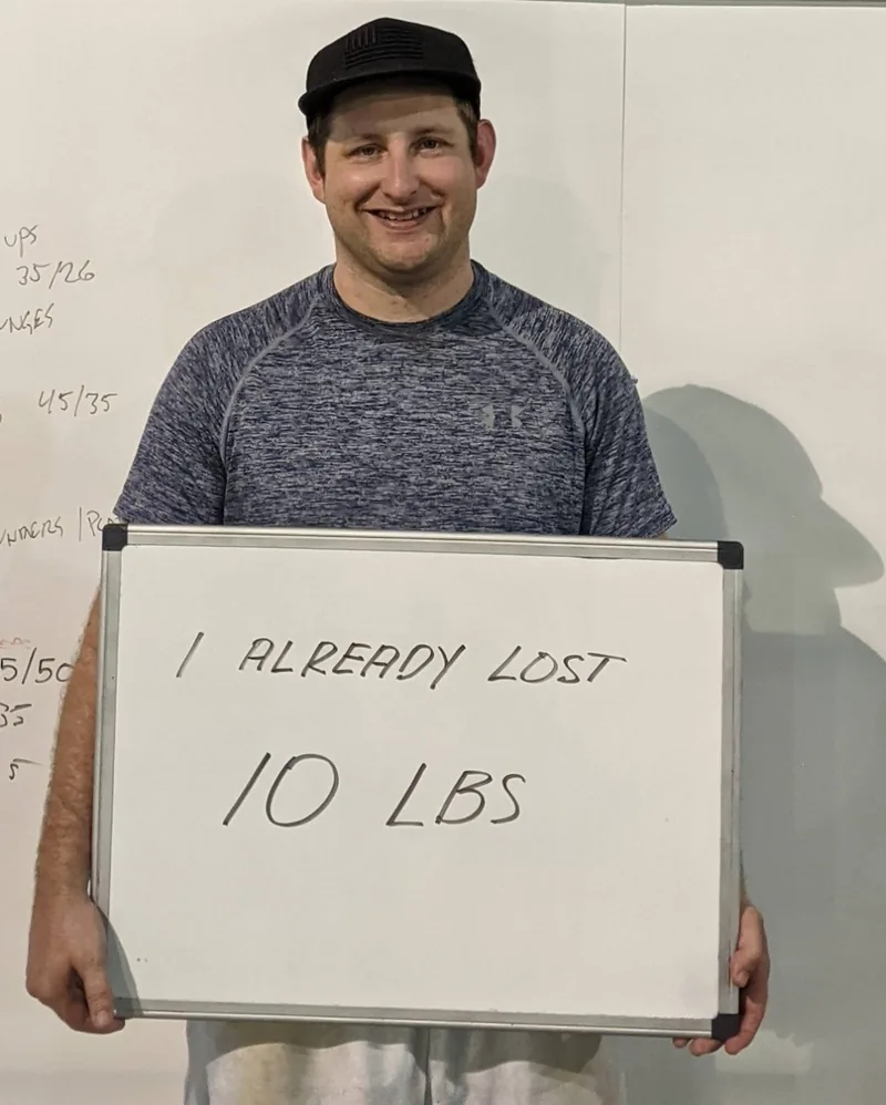 Andre, a Fit 901 client, smiling and holding a board that reads I already lost 10 lbs.