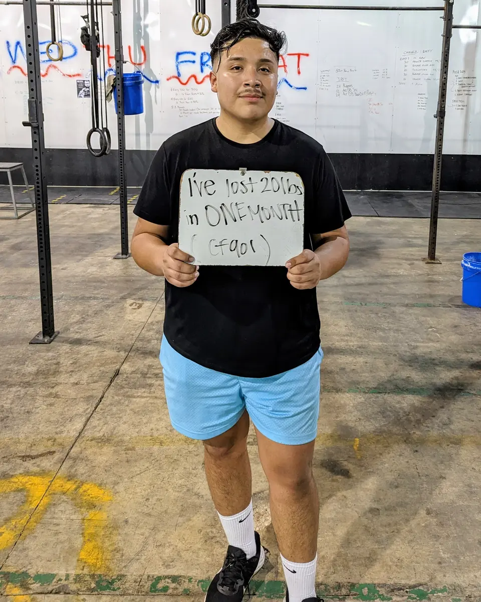 Juan smiling and holding a board that reads I've lost 20 lbs in one month.