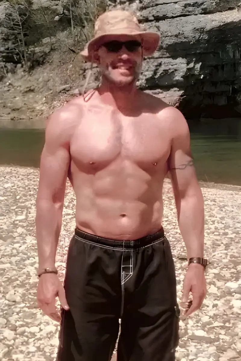 Coach Rob Yahn in his late 40s, lean and muscular, standing by a river.
