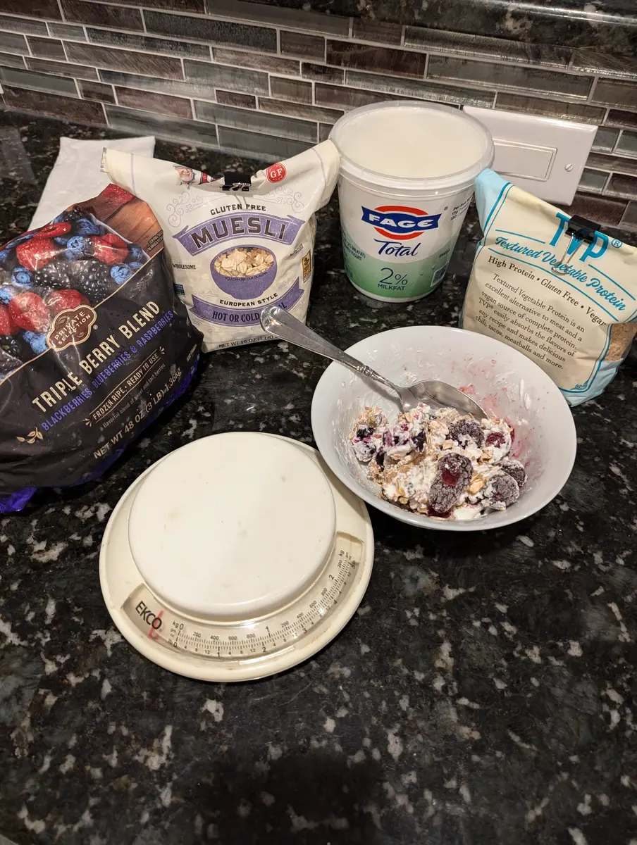 A kitchen scale next to oats, yogurt and berries on a counter.