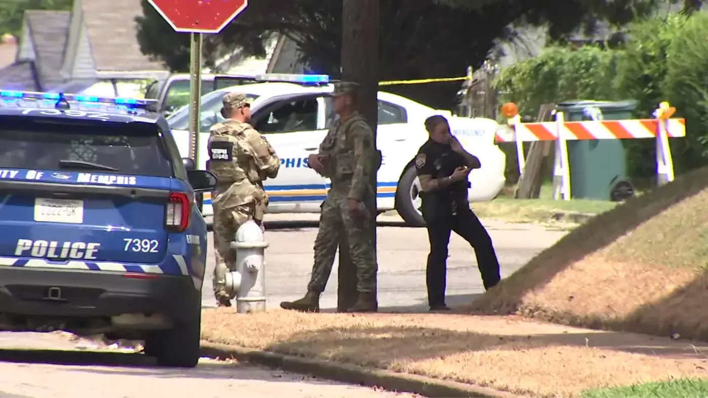 A Memphis police officer and National Guard soldiers on scene beside a police vehicle.