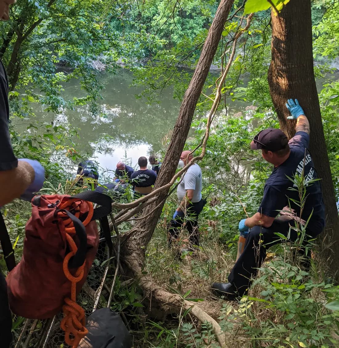 Memphis firefighters working a technical water rescue on a wooded riverbank.